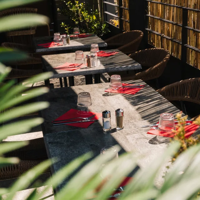 Terrasse du Duplex dressée avec tables, feuillage et serviettes rouges